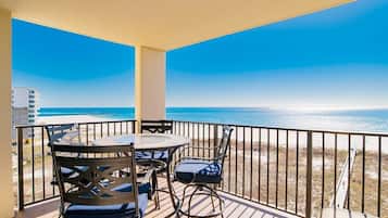 Un balcón con mesa y sillas, con vista a una playa y al océano.