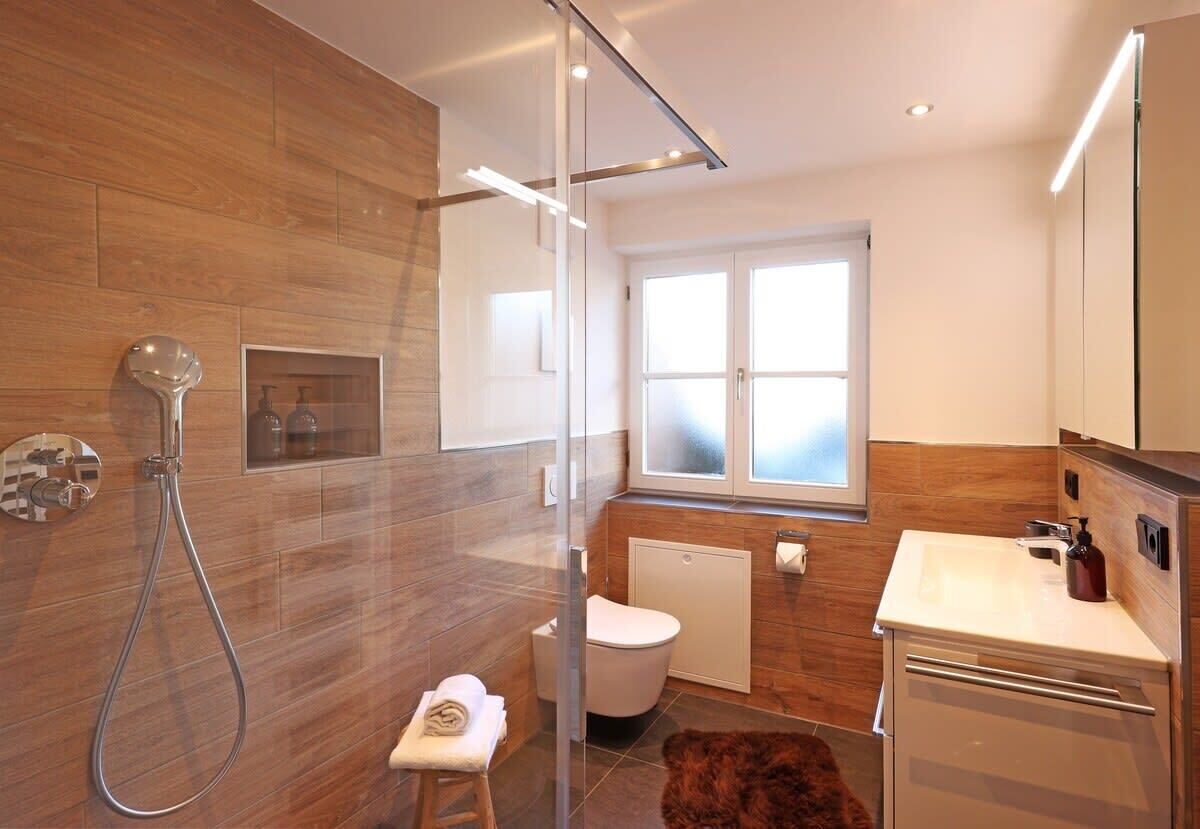 A modern bathroom with a glass shower enclosure, a toilet, and a sink with a mirror.