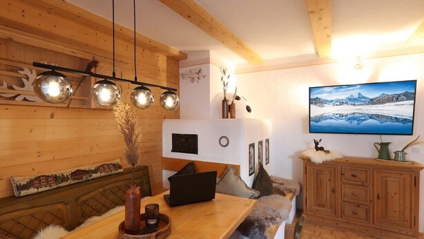 Ett mysigt rum med träväggar, ett träbord, en soffa och en tv som hänger på väggen.