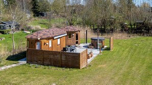Une cabane en bois dotée d’un patio, d’un jacuzzi et d’une petite terrasse.