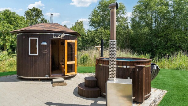 Une cabane en bois avec une porte ouverte, un jacuzzi et un sauna.