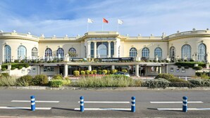 Un grand hôtel à la façade classique, orné de nombreux drapeaux, et doté d’un hall d’entrée bien entretenu.