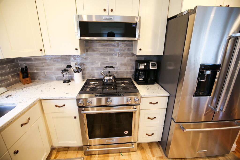 A kitchen with white cabinets, a stainless steel stove, oven, and refrigerator.