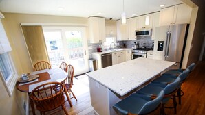 A modern kitchen with a large island, wooden chairs, and a dining table.