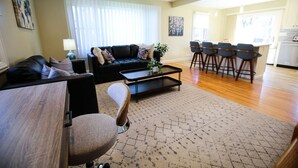 A modern living room with a sofa, coffee table, and bar stools.