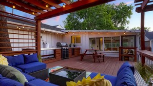 Eine überdachte Terrasse im Freien mit Grill, Sitzgelegenheit und Lichterketten.