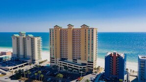 A high-rise hotel with multiple floors, a parking area, and a view of the ocean. - Crystal Shores West 1401 | Guest Favorite! Gorgeous updates! Endless views! (Gulf Shores)
