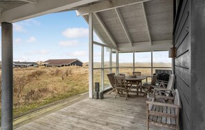 Un espace extérieur abrité, doté d’une terrasse en bois, d’une table avec des chaises et d’un barbecue.