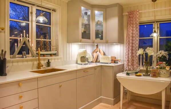 A kitchen with a sink, countertop, cabinets, and a window with a decorative ship model. - 3 bedroom cozy home in Sölvesborg (Sölvesborg)