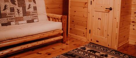 A log cabin room with a wooden bed, a quilt, and a wooden wardrobe.