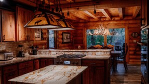Una cucina in stile rustico con mobili impiallacciati in legno, un piano di lavoro in marmo e una grande isola.
