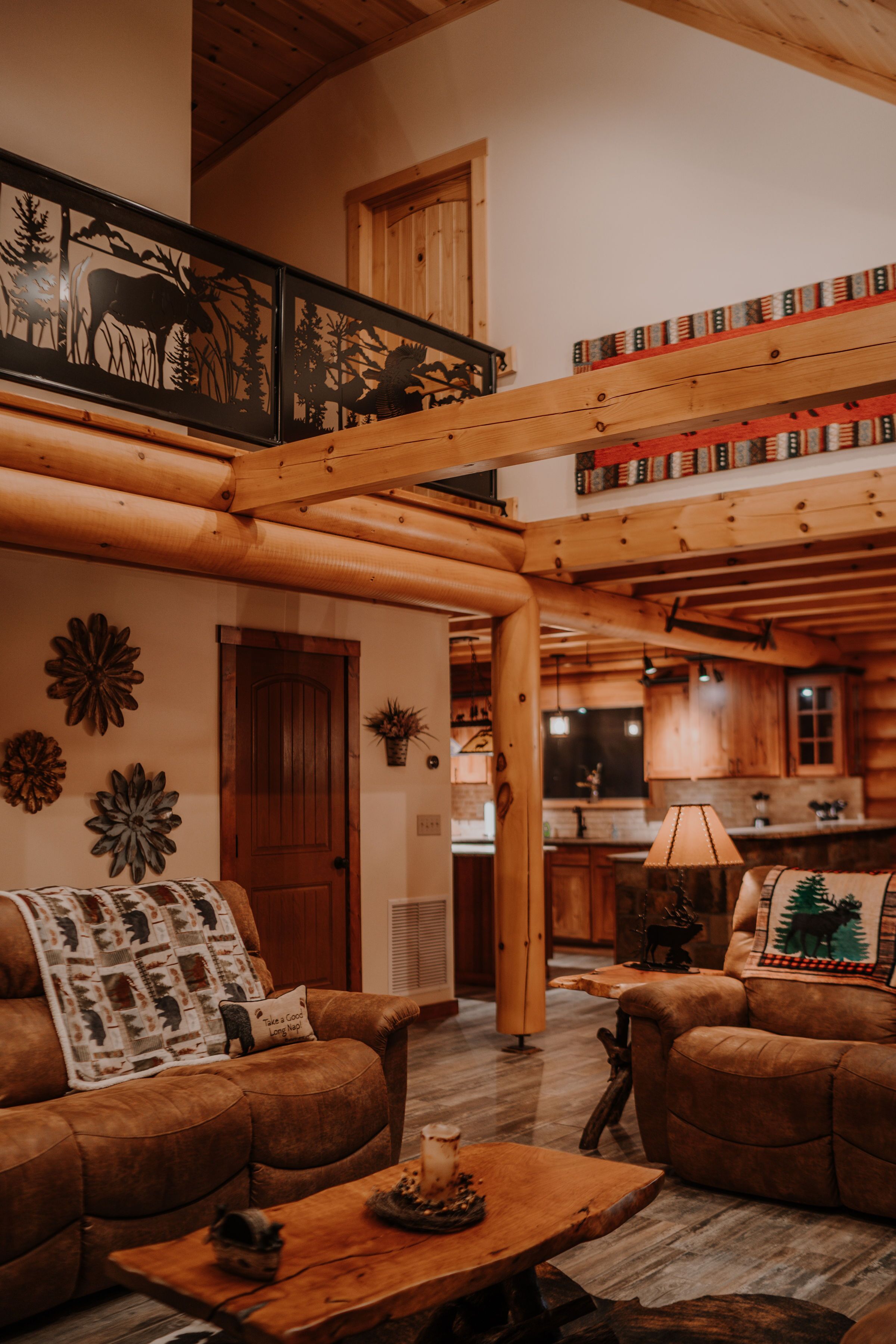 A cozy cabin interior with a wooden staircase, a living room with a sofa and coffee table, and a kitchen area.