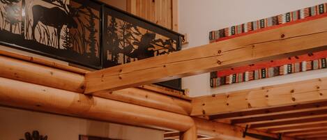 A cozy cabin interior with a wooden staircase, a living room with a sofa and coffee table, and a kitchen area.