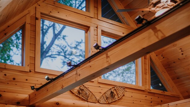 Interno di una baita in legno con ampie finestre, mobili in legno e un'atmosfera rustica.