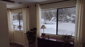 Ein Zimmer mit großem Fenster, einem Nachttisch mit Lampe und einem Blumentopf.