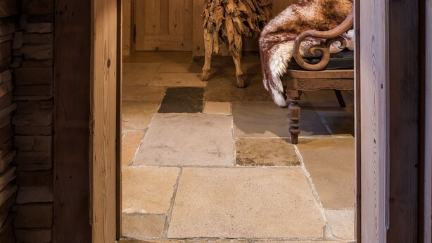 Ein rustikales Interieur mit Holzboden, einer Holztür und einer schlichten Holzbalkendecke.