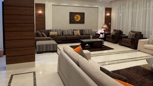 Un salon moderne avec un canapé d’angle, une table basse et un lustre.