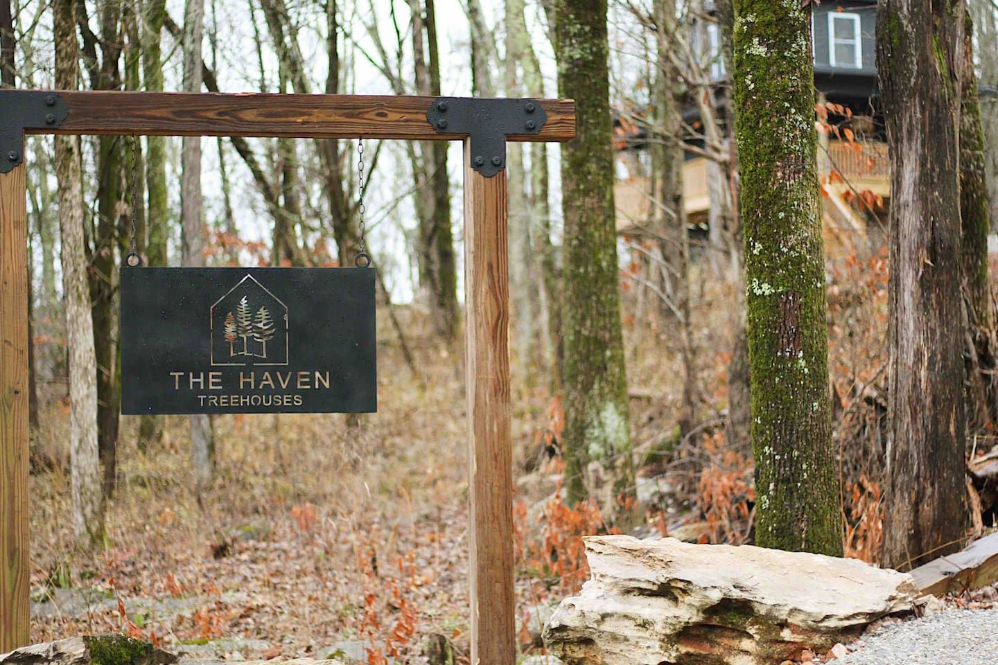 Skilt for 'The Haven Treehouses' i et skovområde.