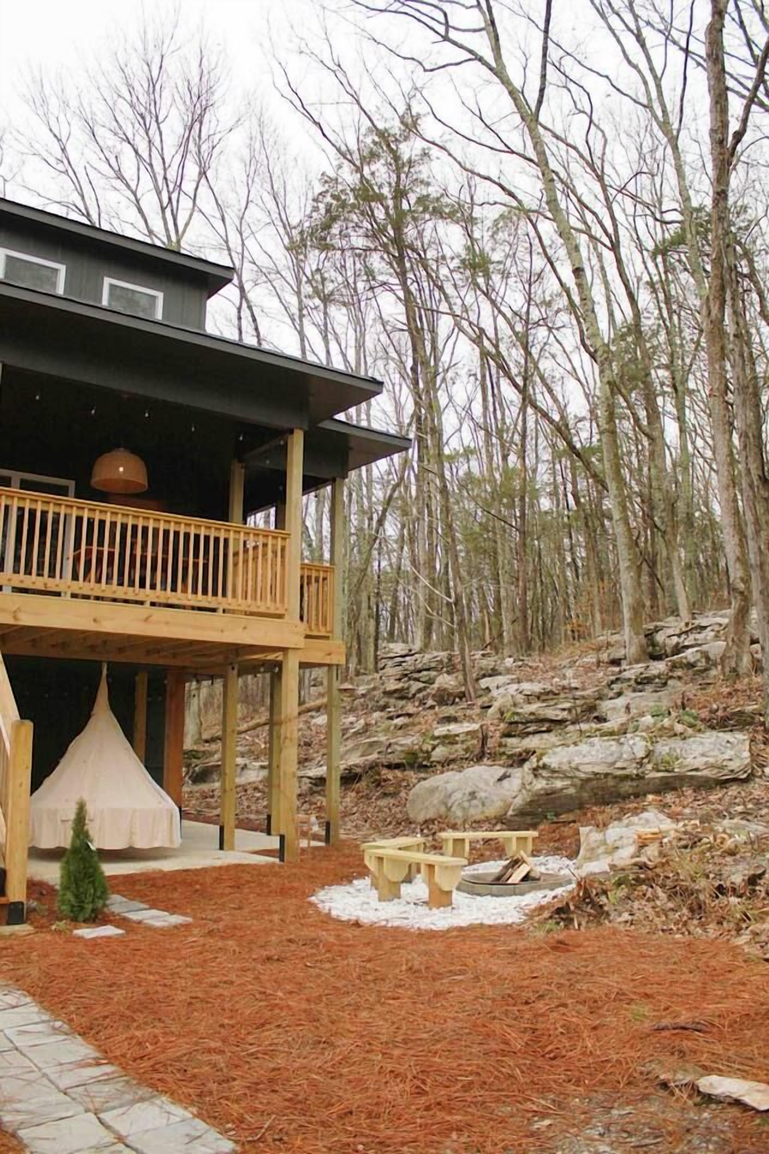 A cabin with a wooden deck and a covered outdoor seating area.