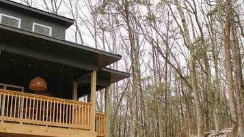 A cabin with a wooden deck and a covered outdoor seating area.