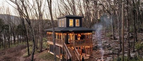 Eine Hütte mit einer Terrasse, einem Kamin und einem Kiesweg.