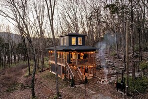 Una cabaña con terraza, chimenea y un sendero de piedra.