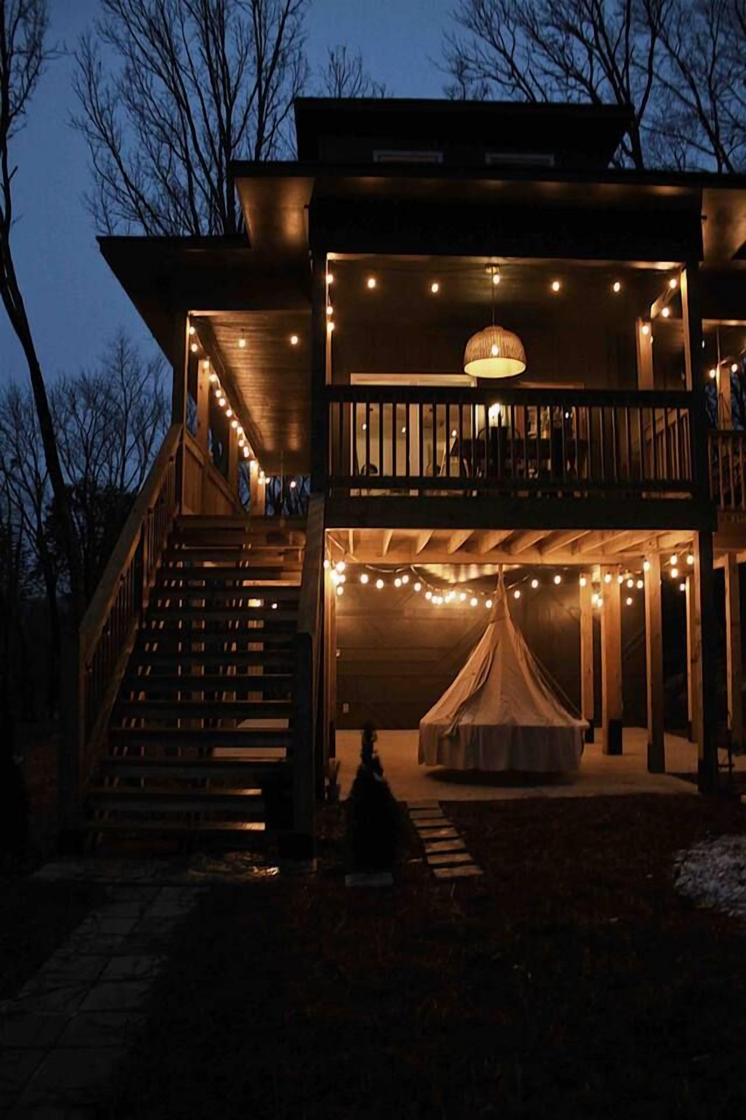 A two-story building with a balcony, outdoor seating area, and string lights.