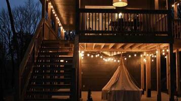A two-story building with a balcony, outdoor seating area, and string lights.