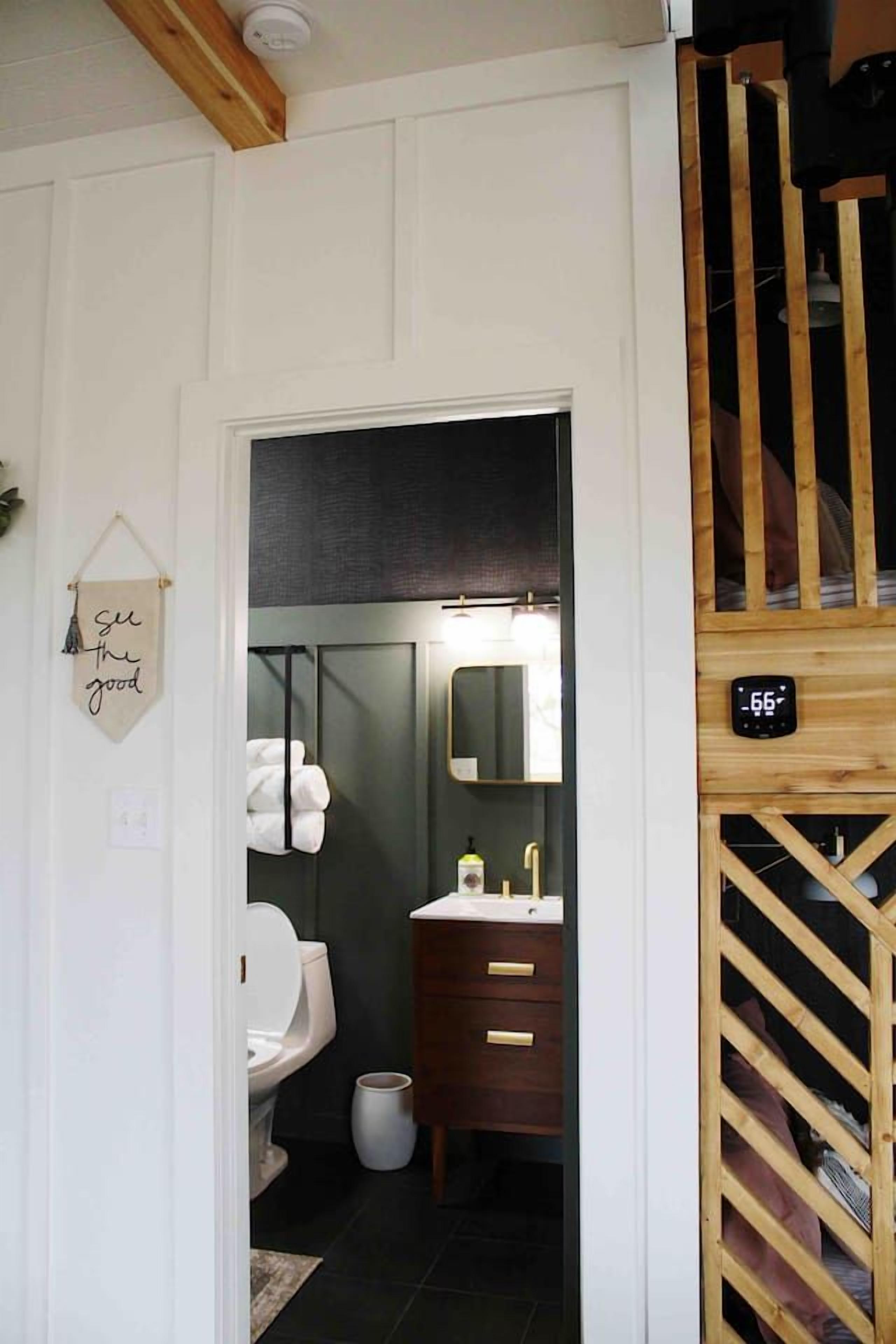 A bathroom with a white toilet, a wooden vanity with a mirror, and a towel rack.