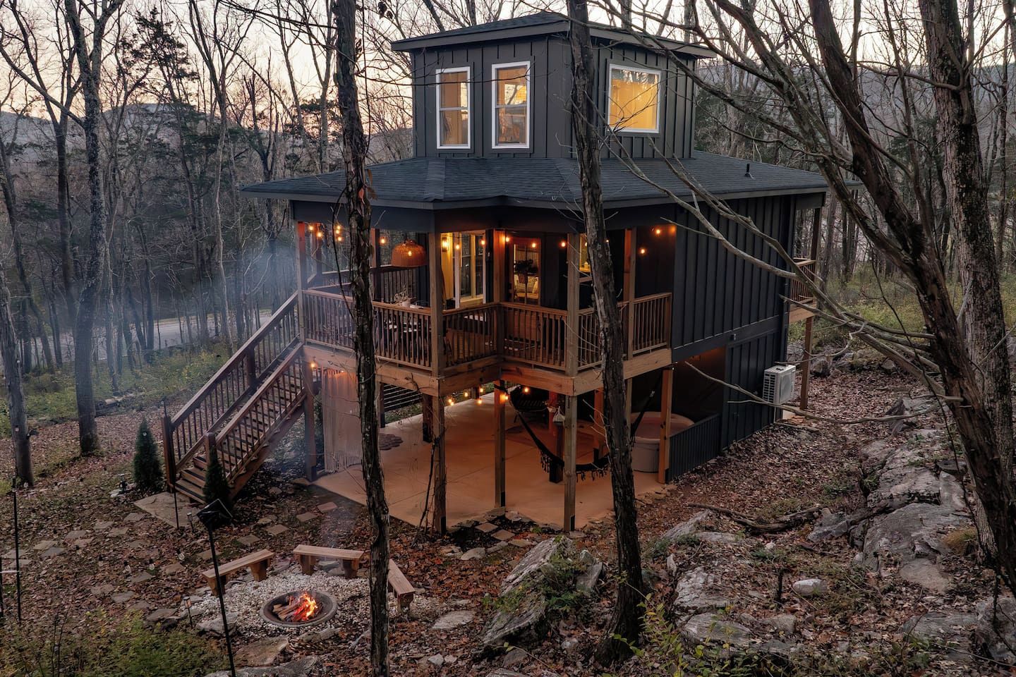 A two-story cabin with a balcony, a fire pit, and a deck.