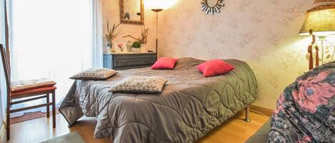A bedroom with a bed, a chair, a dresser, a mirror, and a lamp.