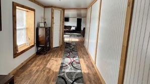 A hallway with wooden flooring, a patterned carpet, and a ceiling light fixture. - Secluded Melrose Escape with Lake Access (Melrose)
