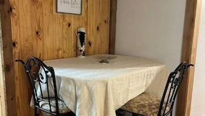 A dining area with a wooden wall, a table covered with a white tablecloth, and two chairs with patterned cushions. - Secluded Melrose Escape with Lake Access (Melrose)