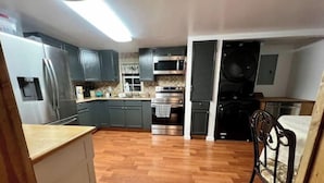 A kitchen with grey cabinets, a stainless steel refrigerator, a microwave, an oven, and a washing machine. - Secluded Melrose Escape with Lake Access (Melrose)
