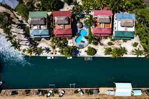 Une vue aérienne d’un complexe hôtelier comprenant plusieurs bâtiments, une piscine et un quai avec des bateaux.