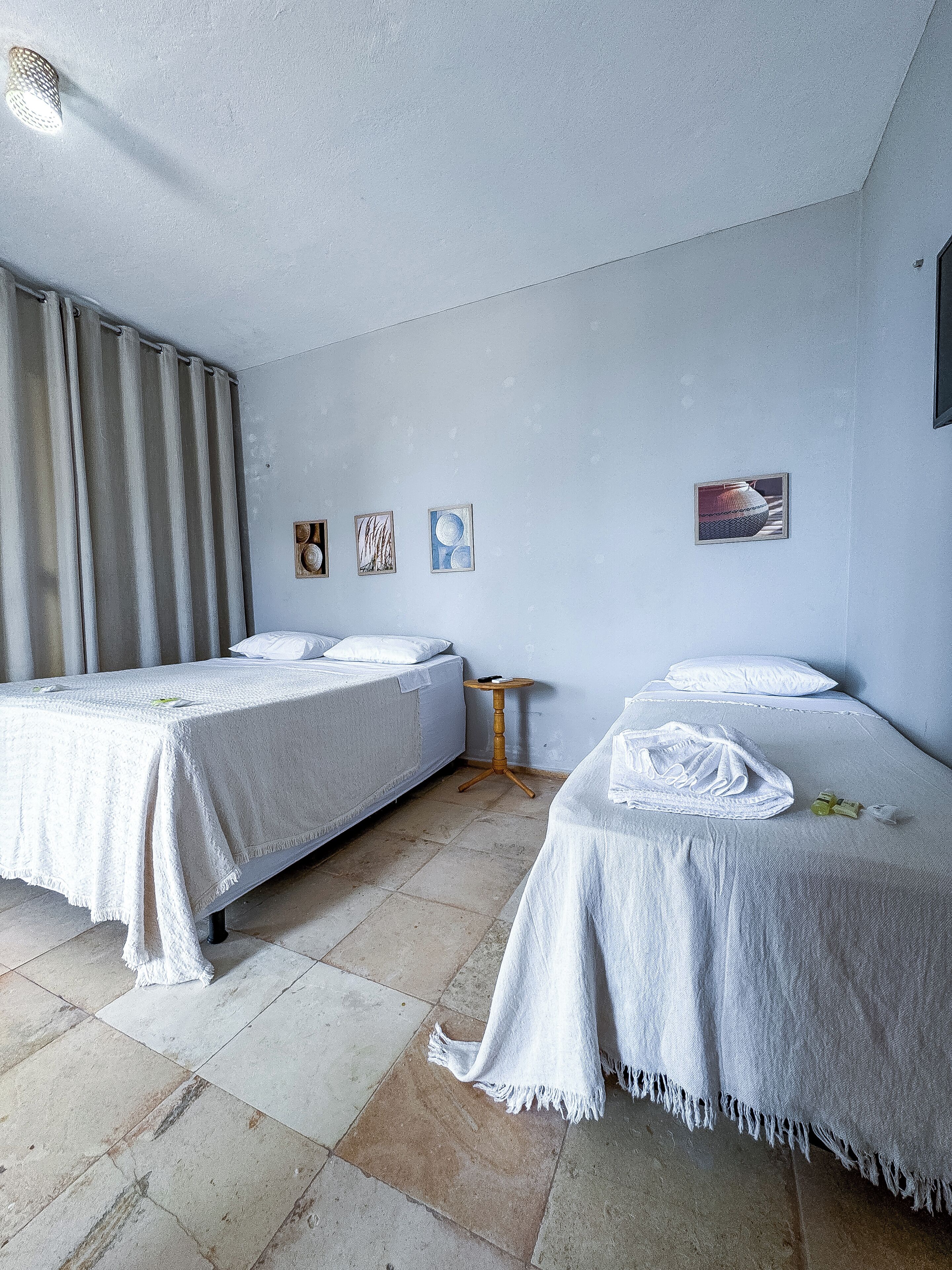 Habitación de hotel con dos camas, una mesita de madera y una pared decorada con tres cuadros.