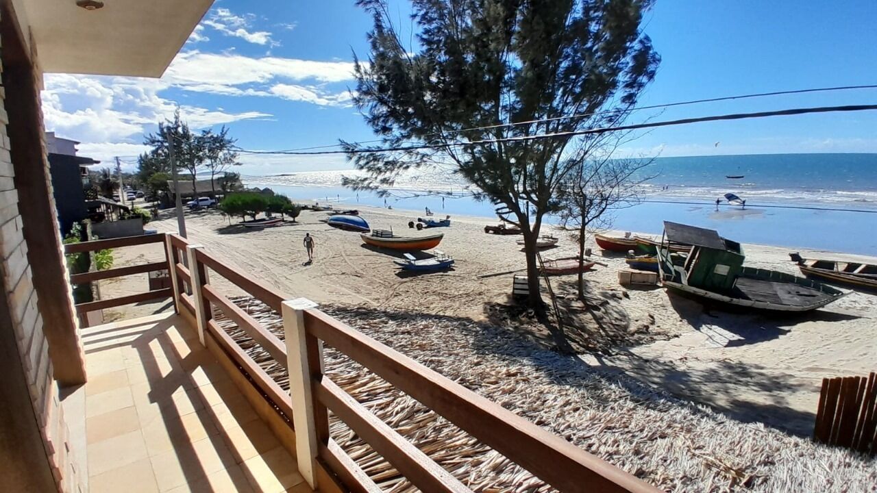 A beach view from a balcony with boats on the sand and a clear sky.