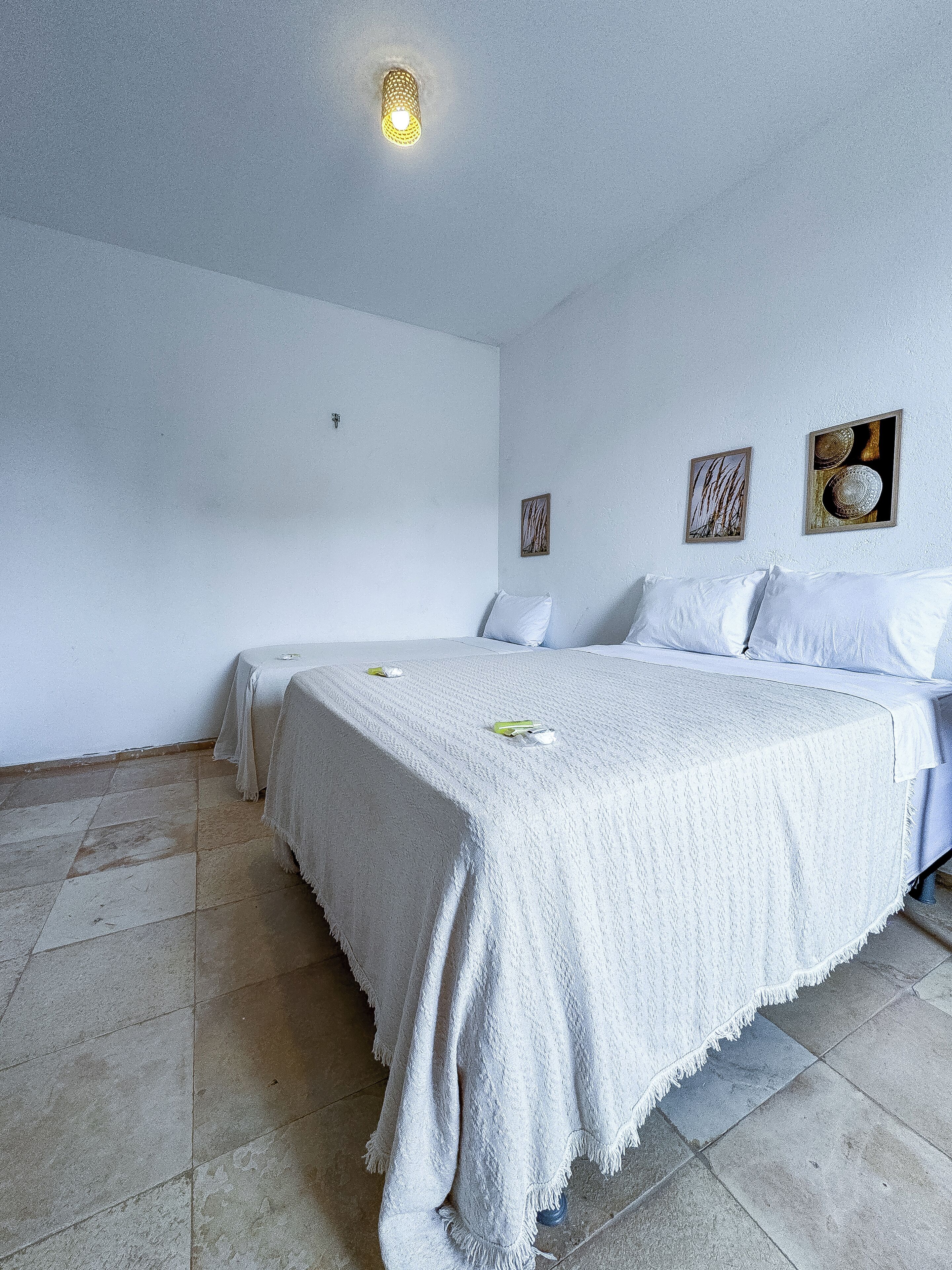 Una habitación con una cama, dos mesitas de noche y una lámpara en el techo.