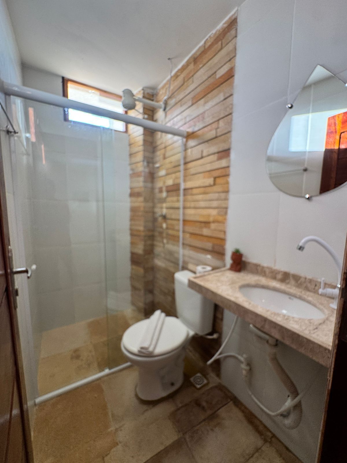 A modern bathroom with a glass-enclosed shower, a toilet, and a sink with a mirror above it.