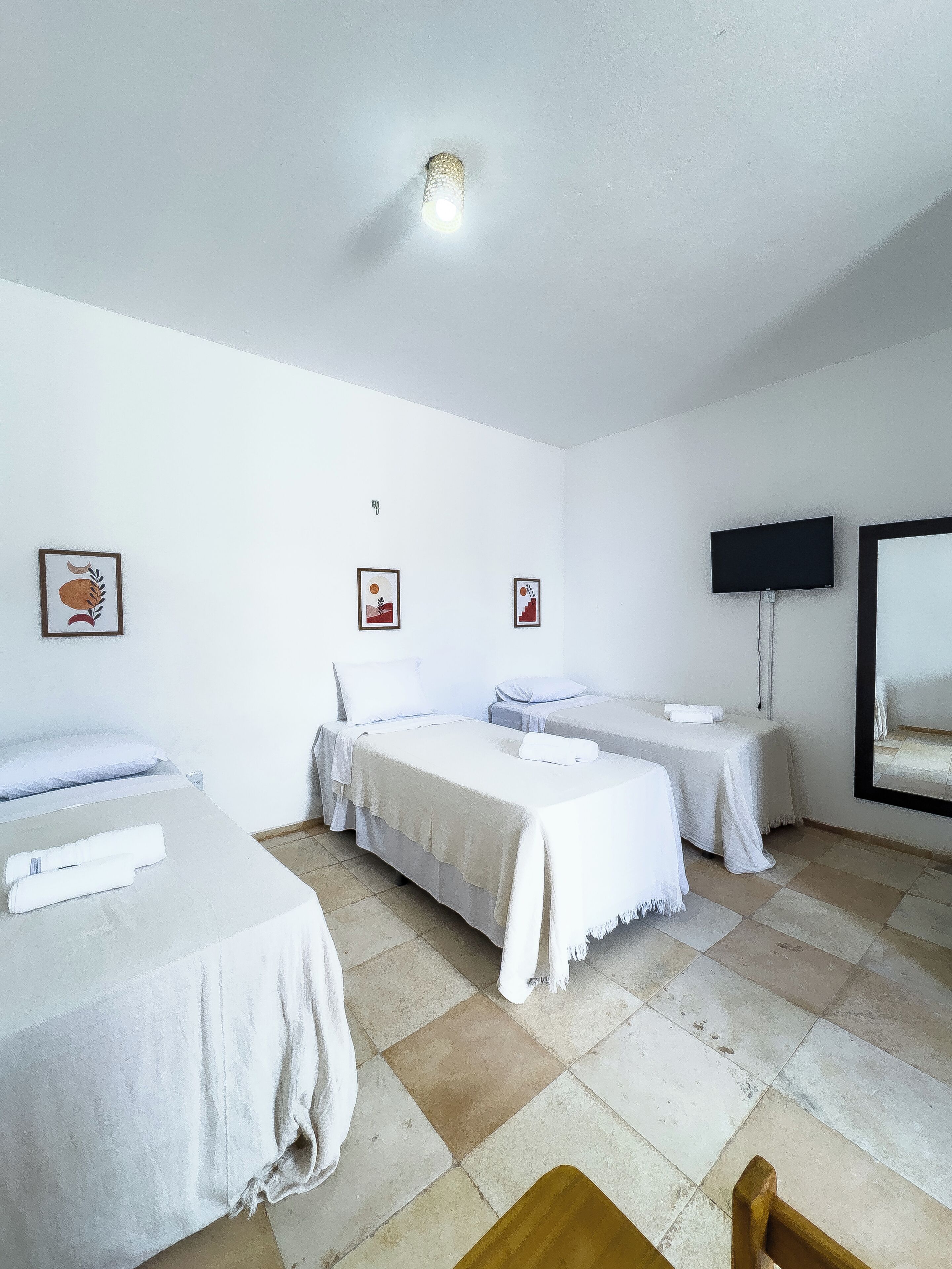 Een hotelkamer met drie bedden, een flatscreen televisie en kunstwerken aan de muur.