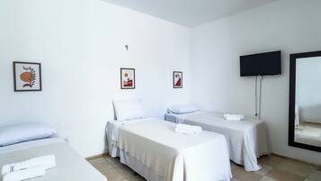 A hotel room with three beds, a flat-screen TV, and artwork on the walls.