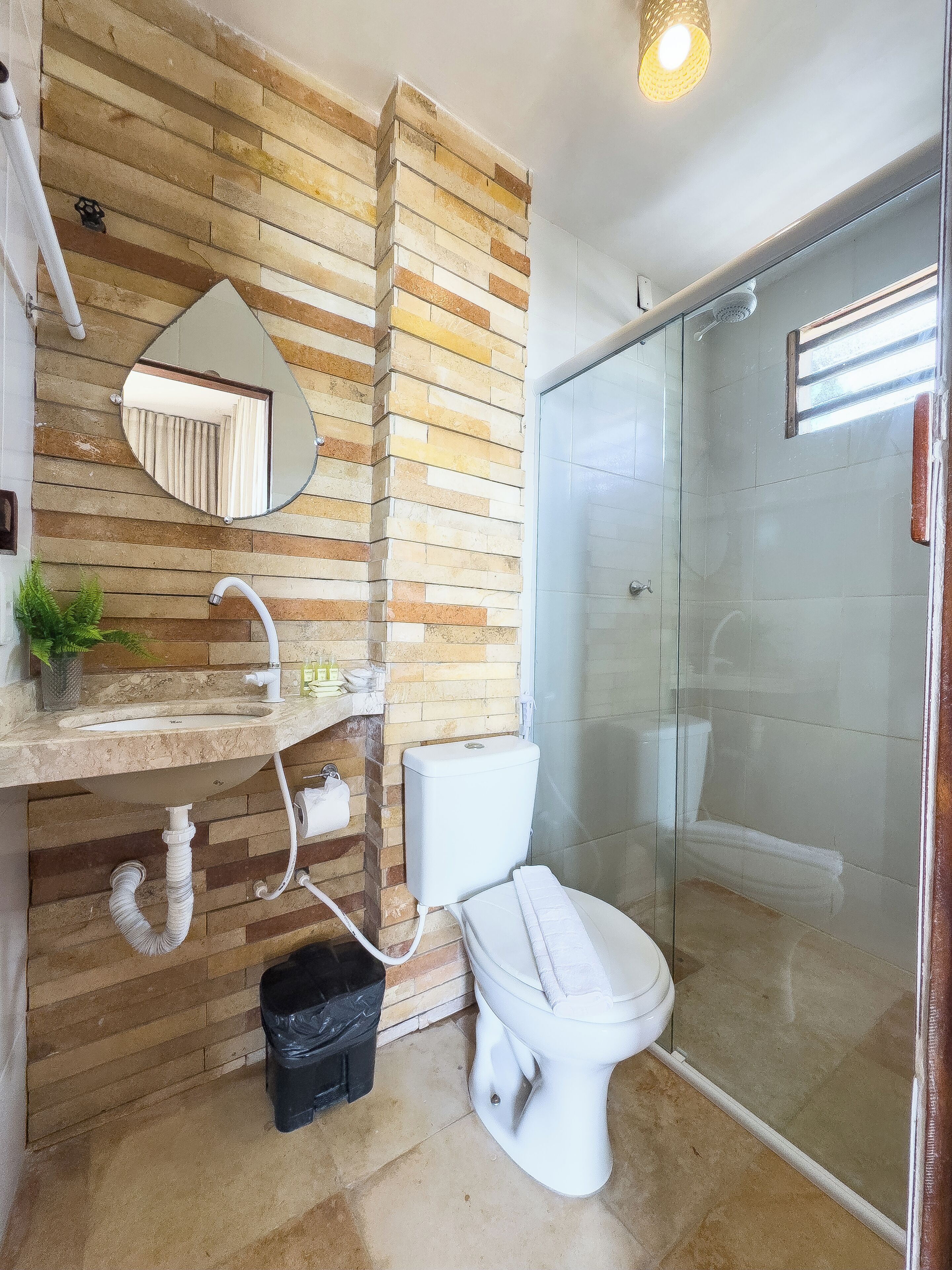 Ein Badezimmer mit Holzwand, Waschbecken, Toilette und einer Duschkabine aus Glas.