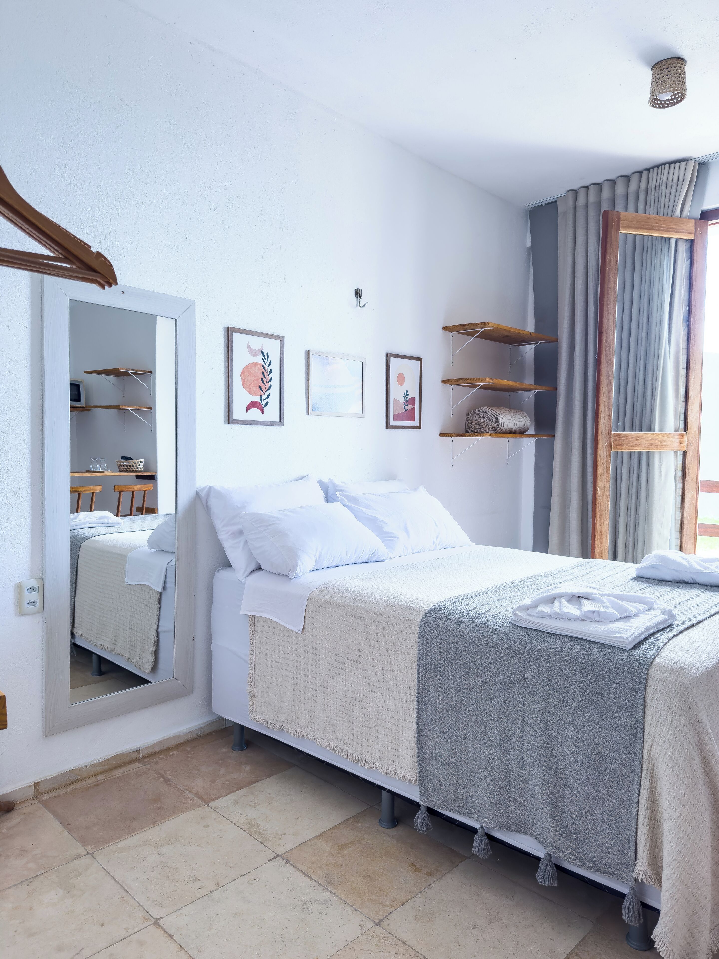 A neatly arranged bedroom with a bed, a mirror, and a wardrobe.