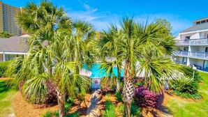 Un hotel con piscina rodeado de palmeras y un cielo azul despejado.