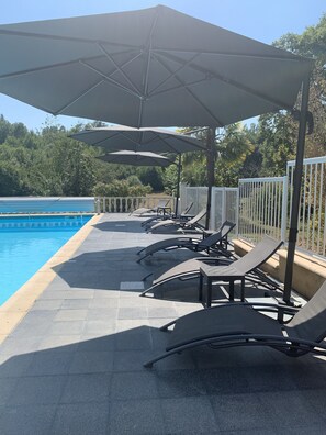 Una piscina al aire libre de temporada, sombrillas, tumbonas