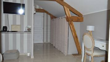Une pièce avec un téléviseur fixé au mur, un bureau avec une lampe, une chaise et un lit avec un rideau à rayures.