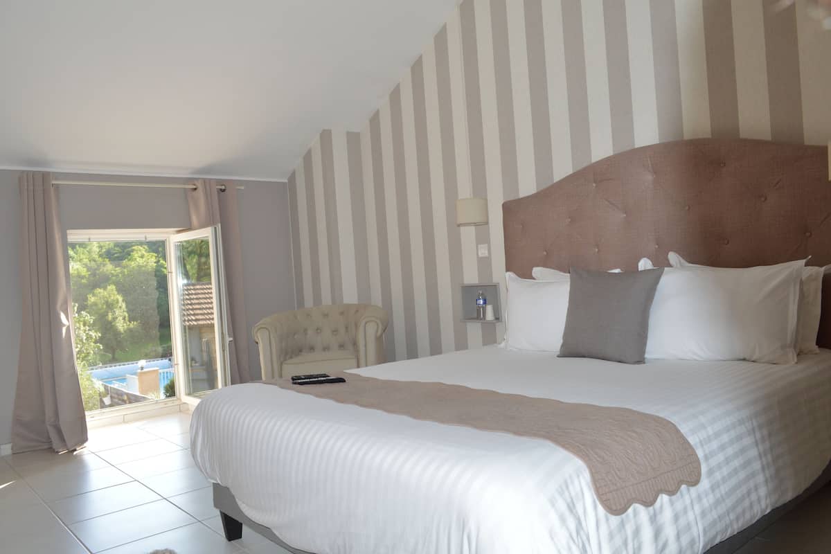 Une chambre d’hôtel avec un grand lit, une chaise, une table de chevet et une vue sur l’extérieur.