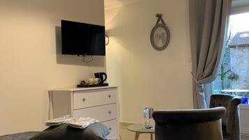 Hotelkamer met een bed, een aan de muur bevestigde televisie, een dressoir, een tafeltje met een lamp en uitzicht buiten door een raam met gordijnen.