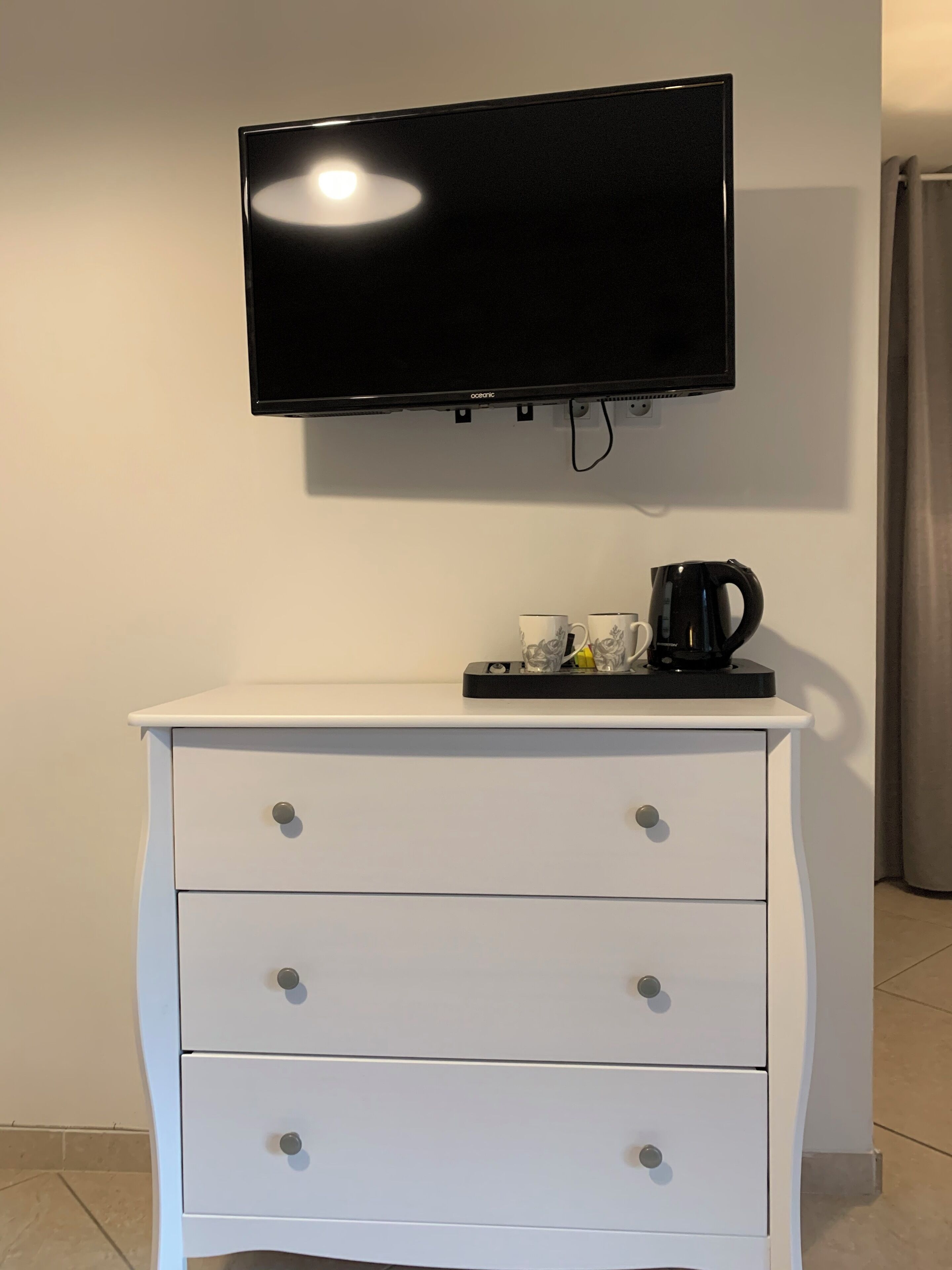 En vit byrå med tre lådor och en platt-TV som är monterad ovanför.