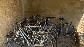 Varias bicicletas estacionadas junto a un muro de piedra en un espacio cubierto.